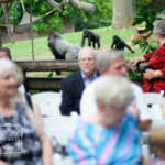 A group of older guests seated for an even in front of a gorilla habitat.