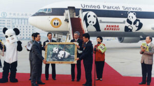 Chinese delegates hold a photo of Lun Lun and Yang Yang outside the panda express plane