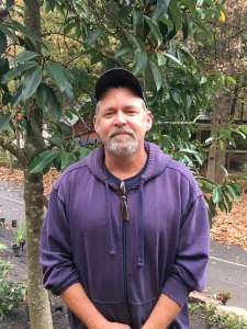 Horticulturist Hal poses in front of leaves.