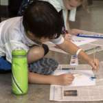 A boy sits on the floor and paints.