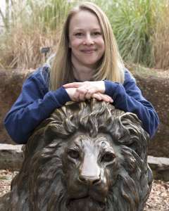 A Zoo Atlanta teammate poses on a lion sculpture.
