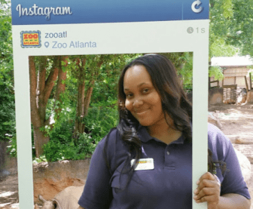 A Zoo Atlanta teammate poses with a large Instagram frame.