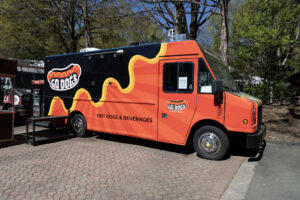 A red and black food truck sits on a bricked path.