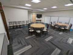 A wide shot showing the event space the Elephant Room in Savanna Hall. Two tables set with chairs are in the middle of the event space.