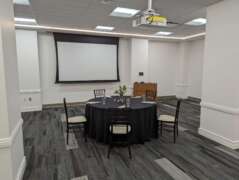 A wide shot showing the event space the Zebra Room in Savanna Hall. A table set with chairs are in the middle of the event space.