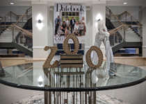 A table in the foyer of Savanna Hall decorated with letters that spell Zoo. In the background is a large print out of the cover of an issue of Modern Luxury Datebook and a stilted acrobat in a zebra costume.