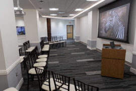 A conference room set up with rows of chairs facing a digital presentation screen.